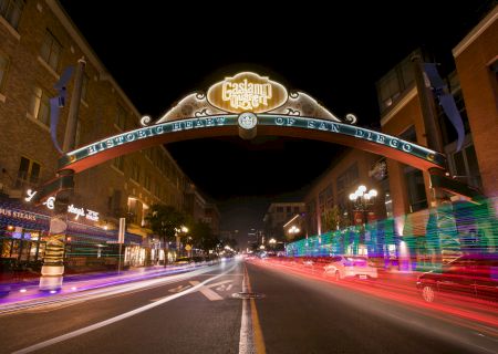 The image shows the illuminated entrance arch to the Gaslamp Quarter in San Diego at night, with blurred lights from passing vehicles.