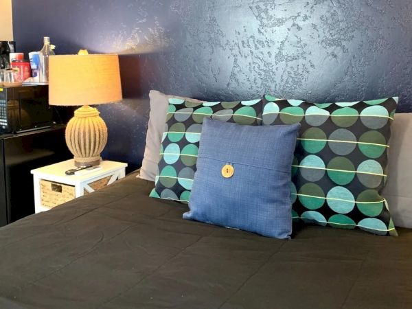 A neatly made bed with decorative pillows, a lamp on a small white nightstand, and a blue wall adorned with starfish and sea-themed decor.
